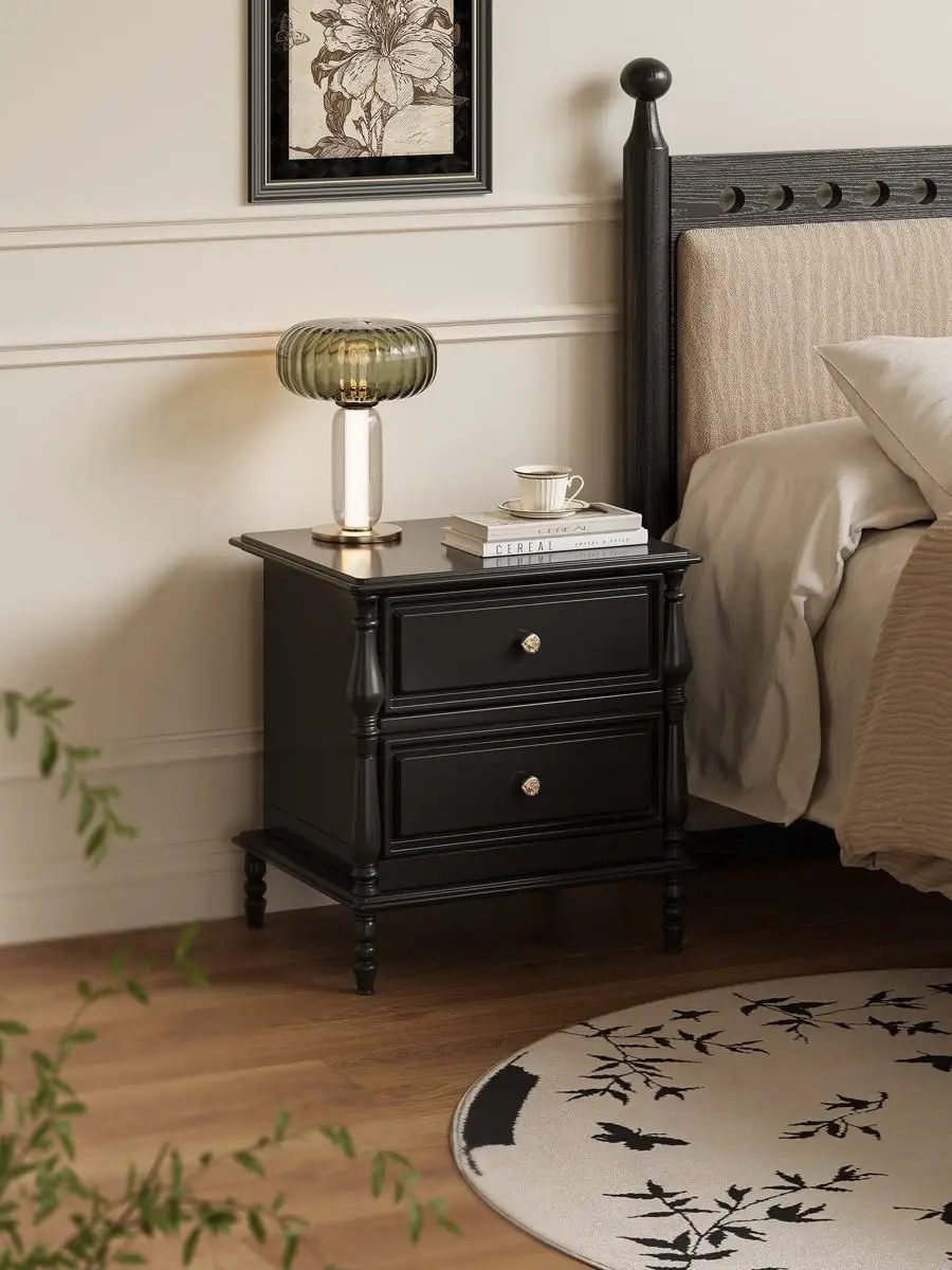 black classical-detail bedside cabinet shown with surrounding furniture for scale