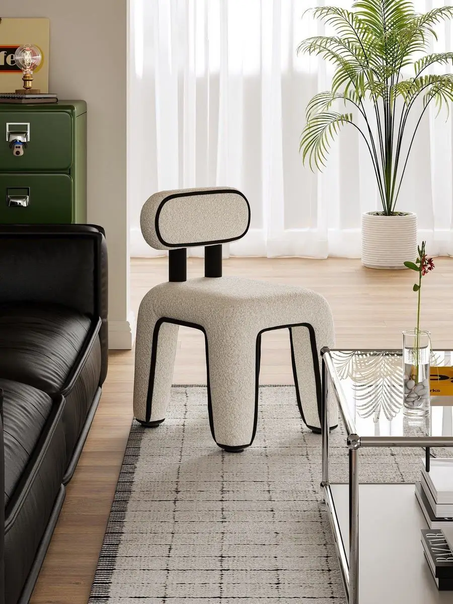 Front view of the piped bouclé chair beside a black leather sofa